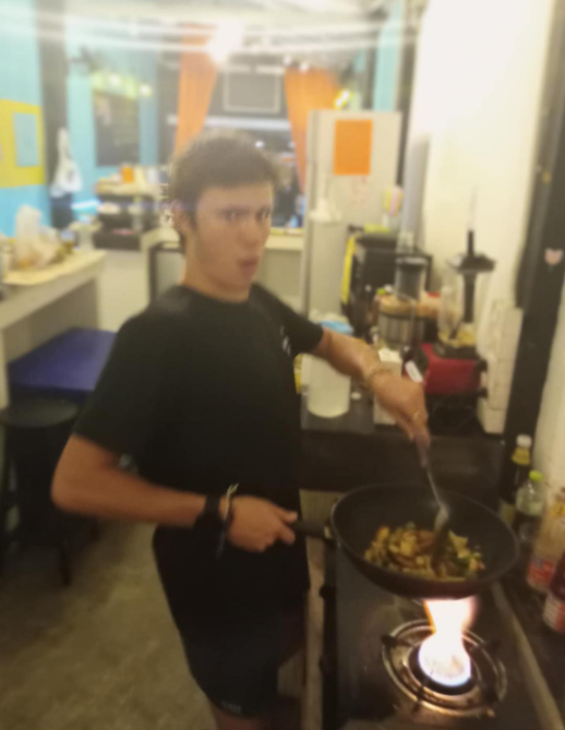 Volunteer cooking over an open flame in the wok — Aurora, a top restaurant in Pai (healthy Pai restaurant, health-focused)