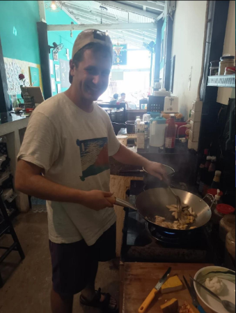 Volunteer happily tossing food in the wok — Aurora, a top restaurant in Pai (healthy Pai restaurant, health-focused)